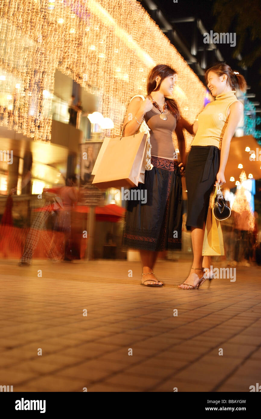 Young women standing side by side, carrying shopping bags Stock Photo ...