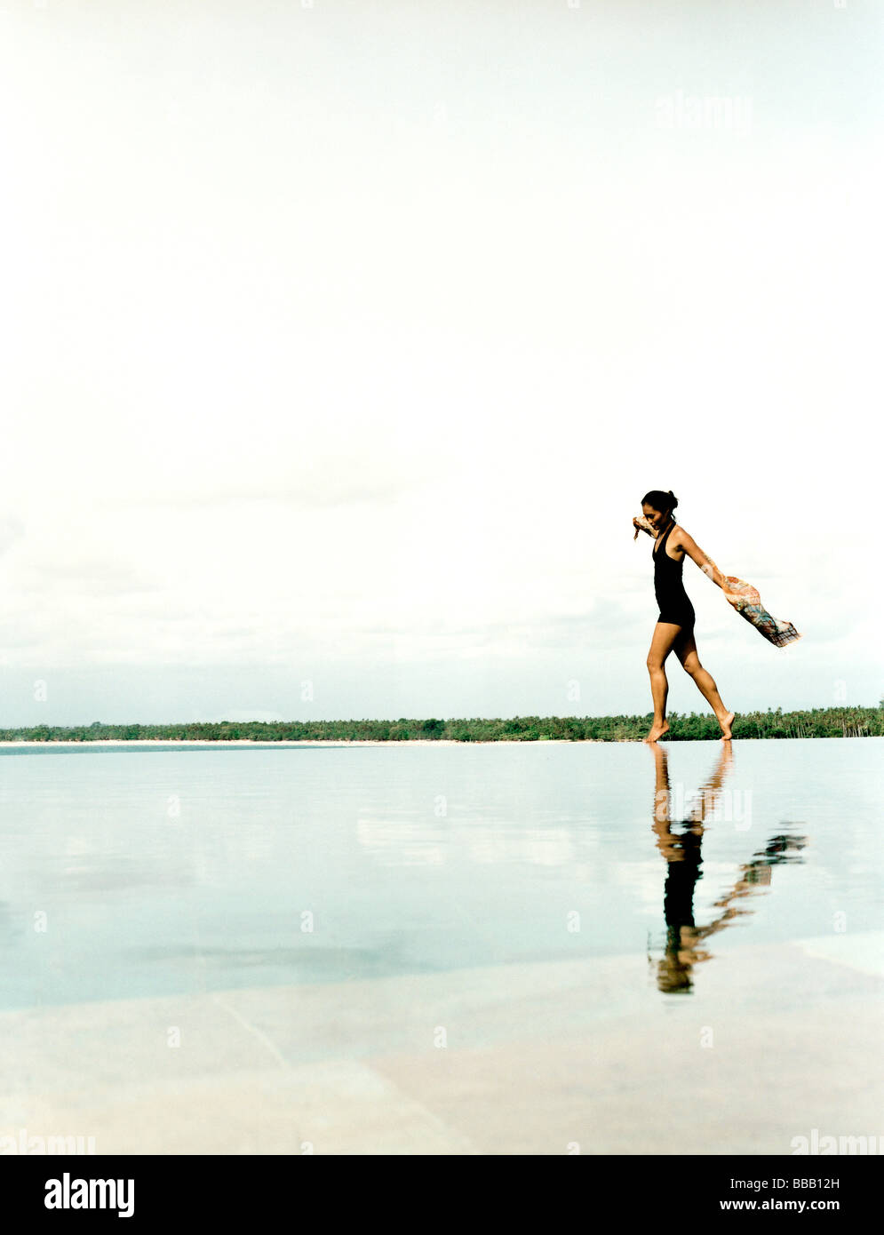 Woman running on water's edge with reflection. Stock Photo