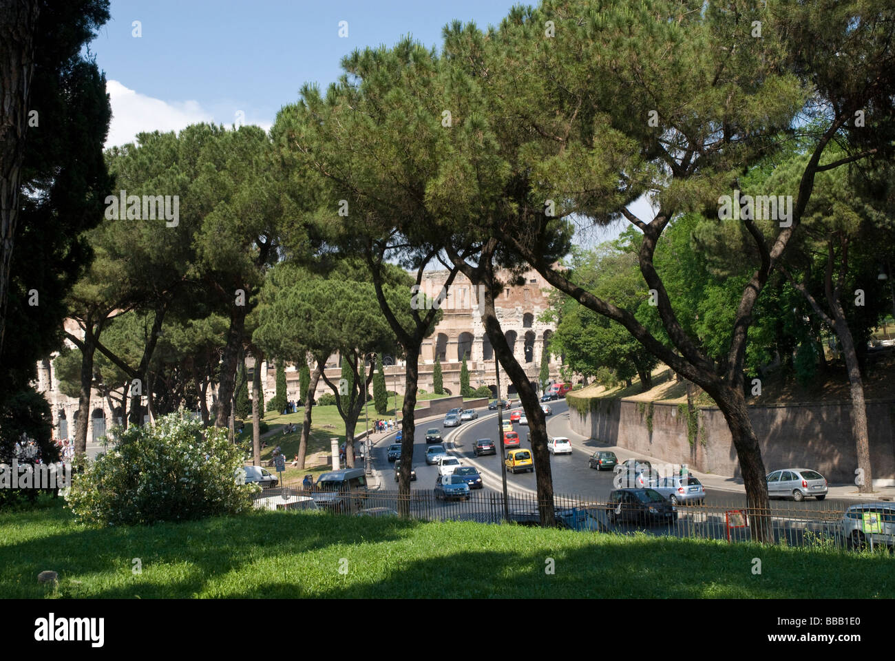 Colosseum,  Colosseo, Rome glimpsed through trees and past the busy road  that surrounds it Stock Photo