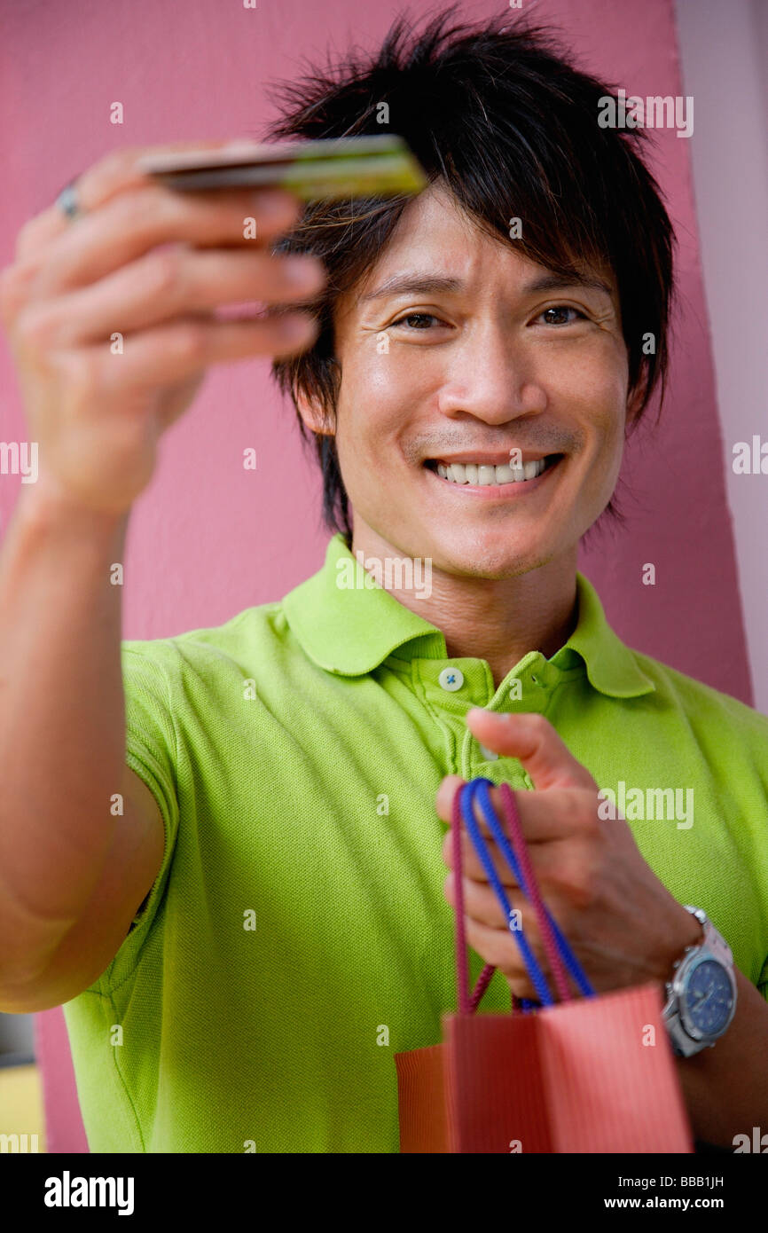 A man holds out his credit card as he holds shopping bags Stock Photo