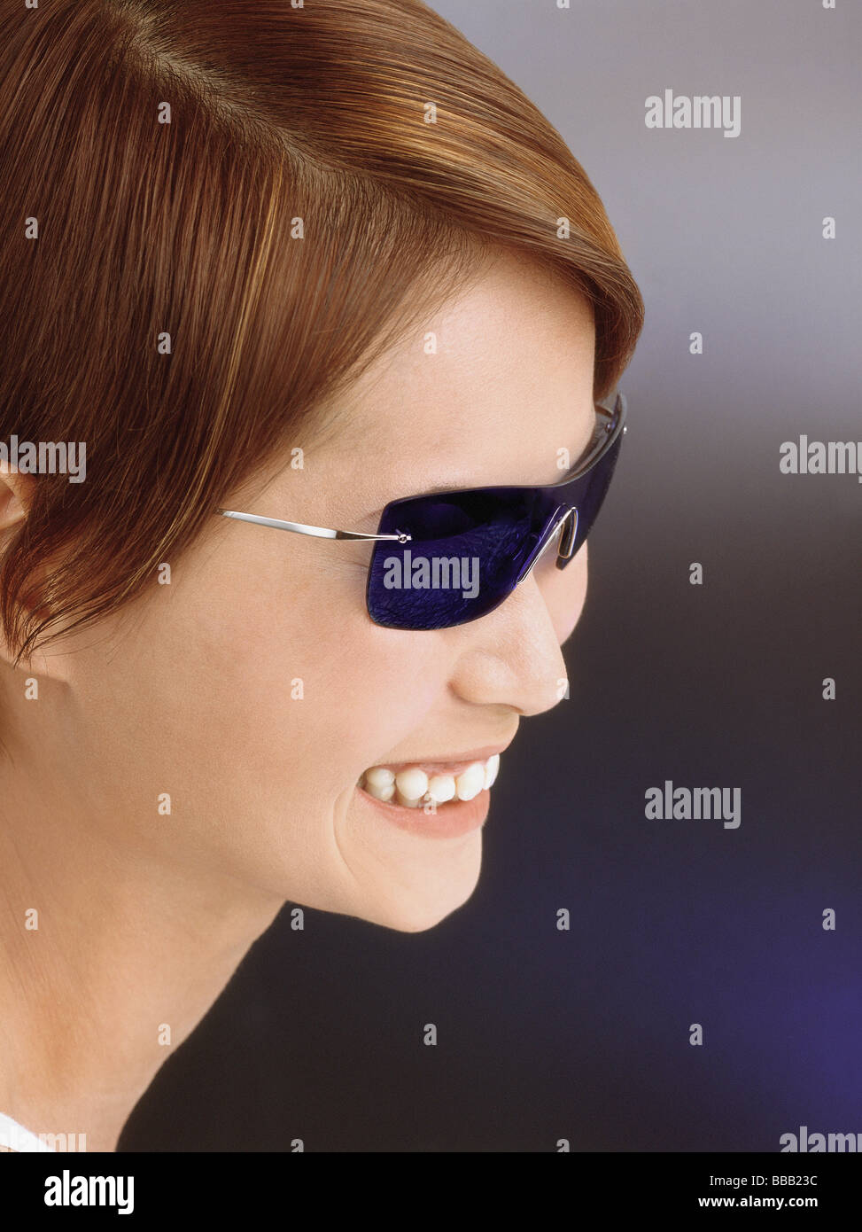 Young woman wearing blue tinted sunglasses, smiling Stock Photo