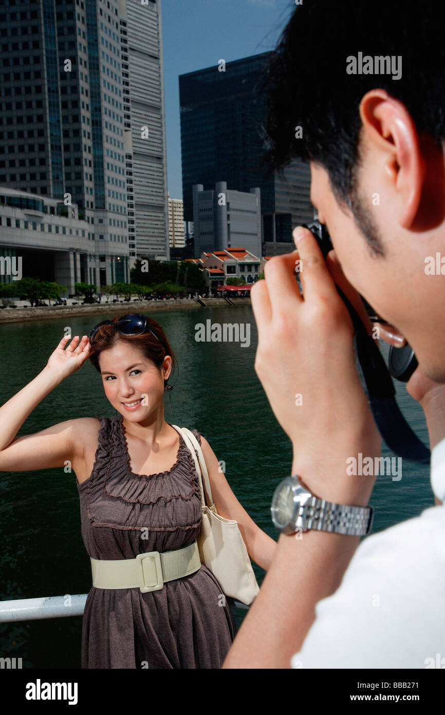 A man takes a photo of his girlfriend with the city in the background Stock Photo