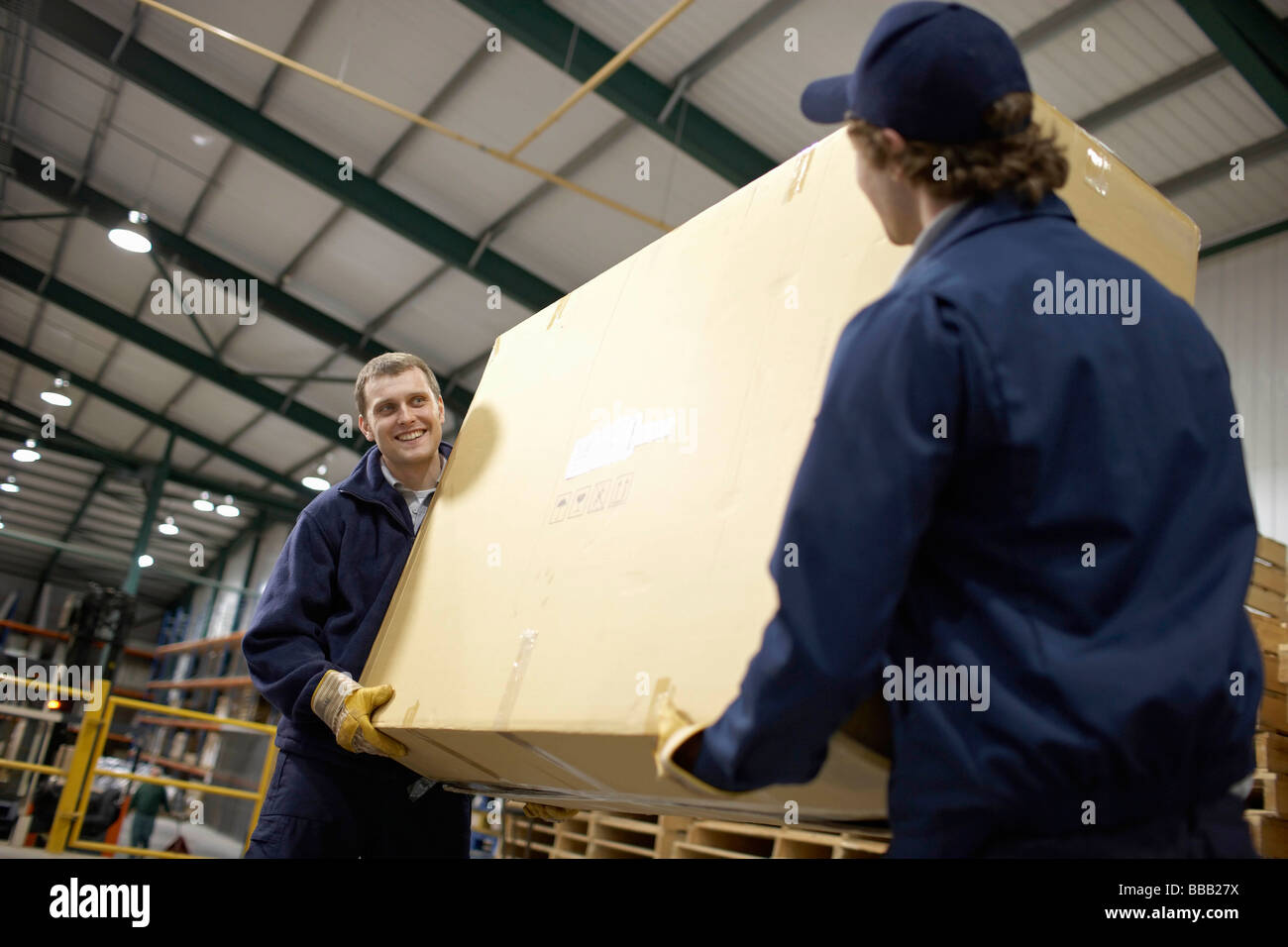 Two workers carrying large box Stock Photo Alamy