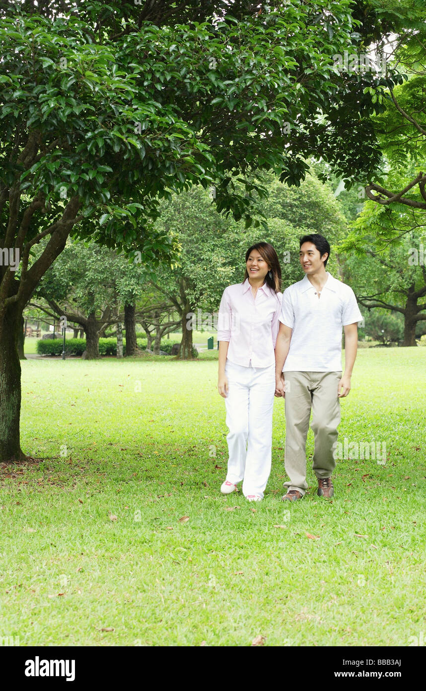 Couple holding hands, walking across park Stock Photo - Alamy