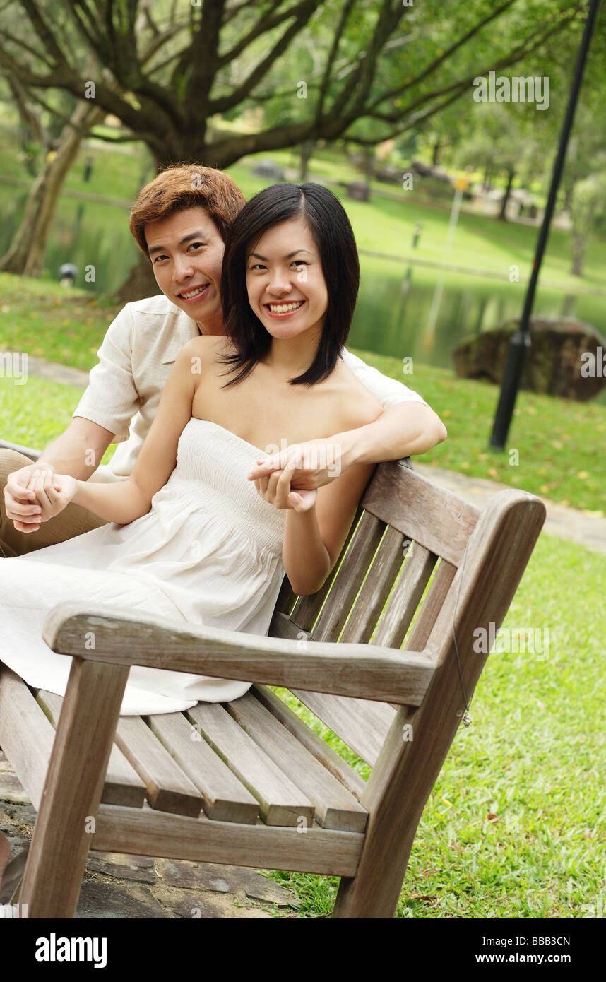 Couple sitting on park bench, looking at camera Stock Photo - Alamy
