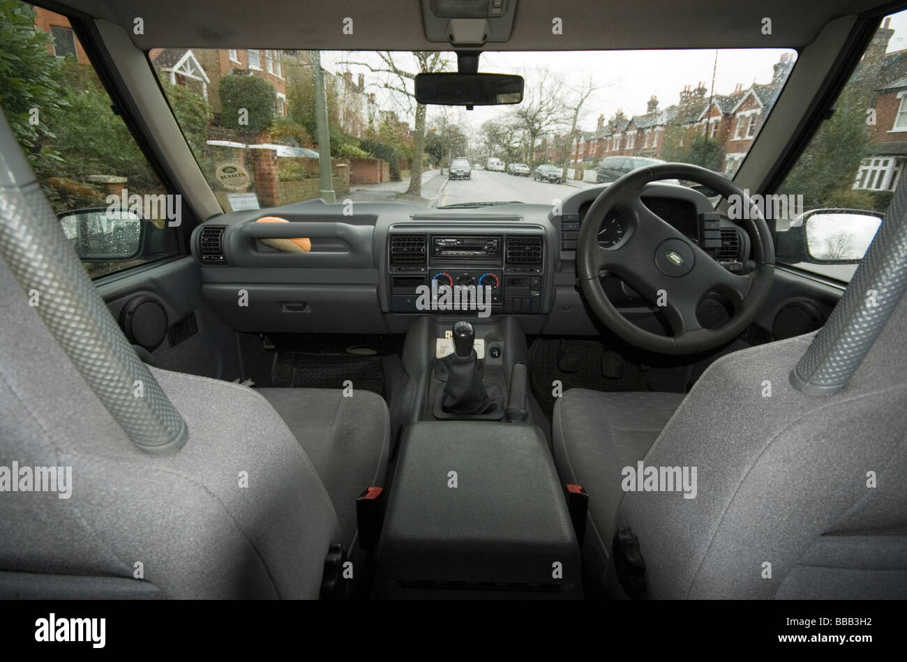 Dashboard of Land Rover Discovery and suburban street seen through windscreen. Stock Photo