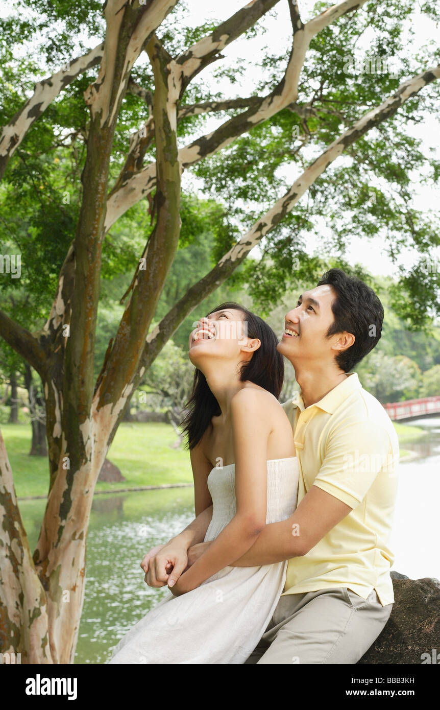 Woman sitting on mans lap, man embracing her, both looking up Stock Photo -  Alamy