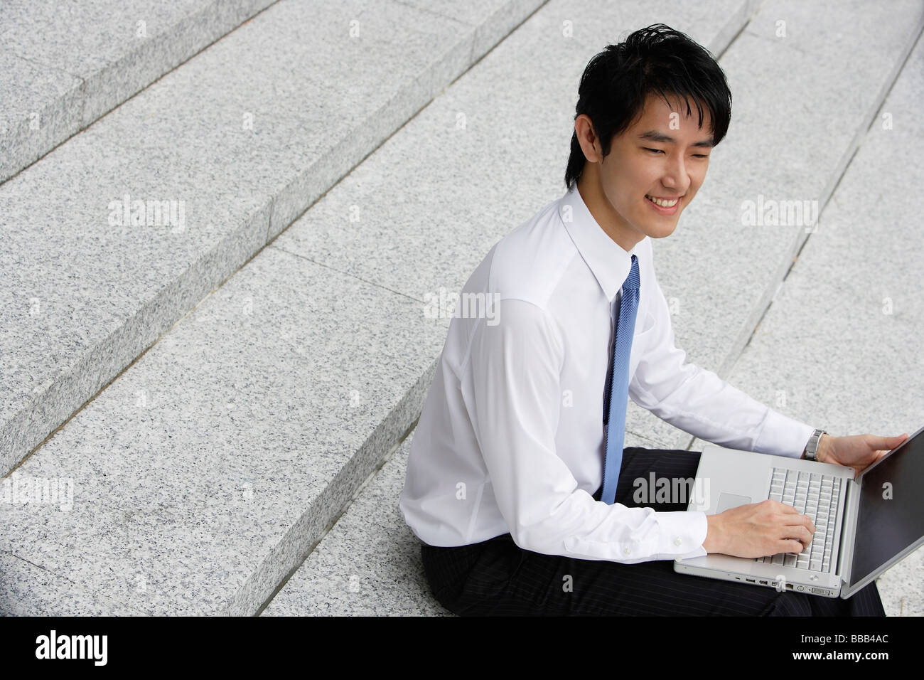 Businessman sitting on steps ans working on laptop Stock Photo