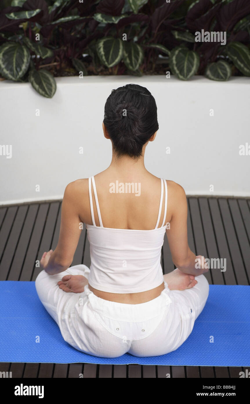 Woman sitting in yoga position, meditating, rear view Stock Photo - Alamy