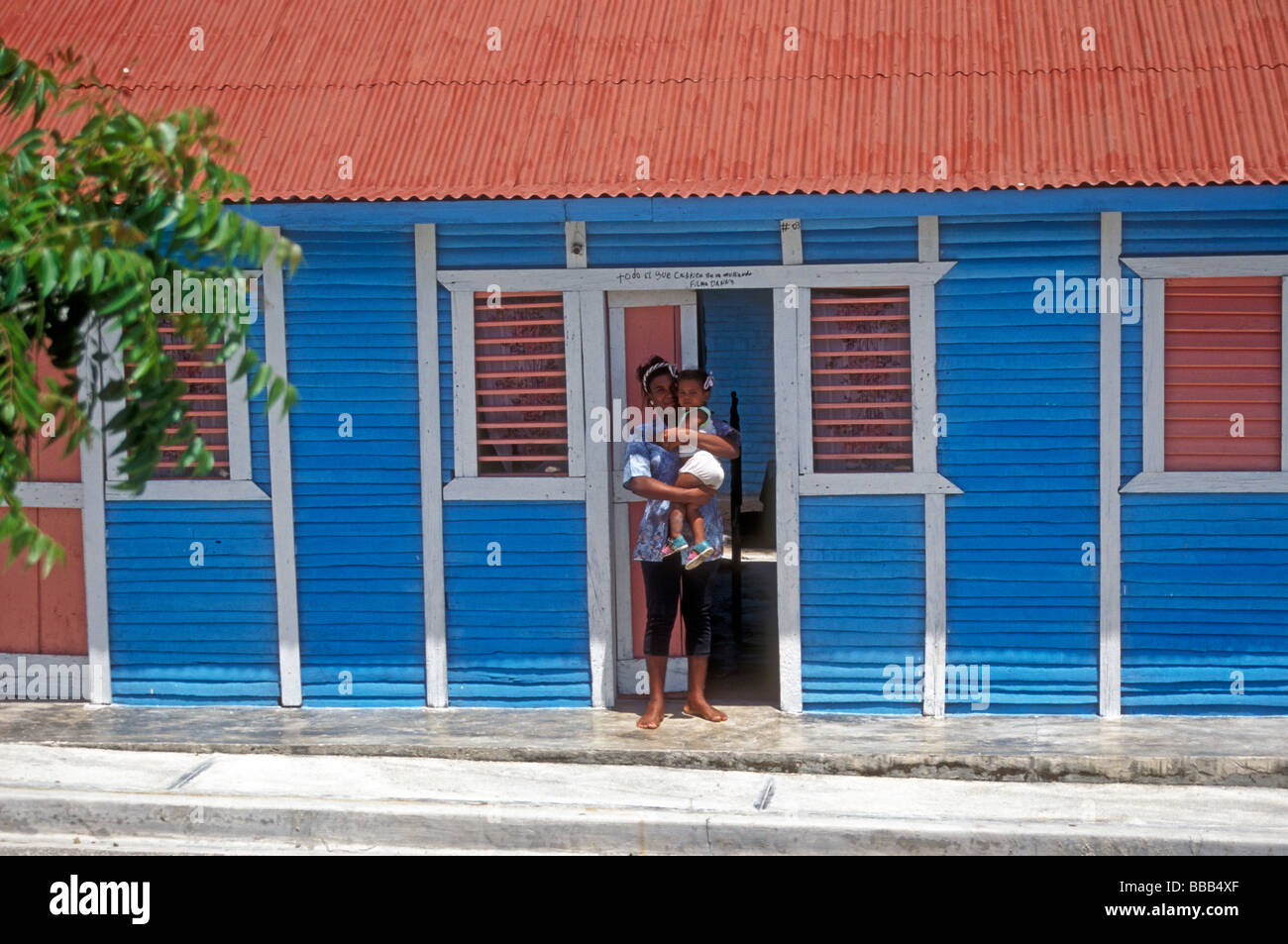 Mother and daughter outside their colorful wooden house in rural Barahona Dominican Republic Stock Photo