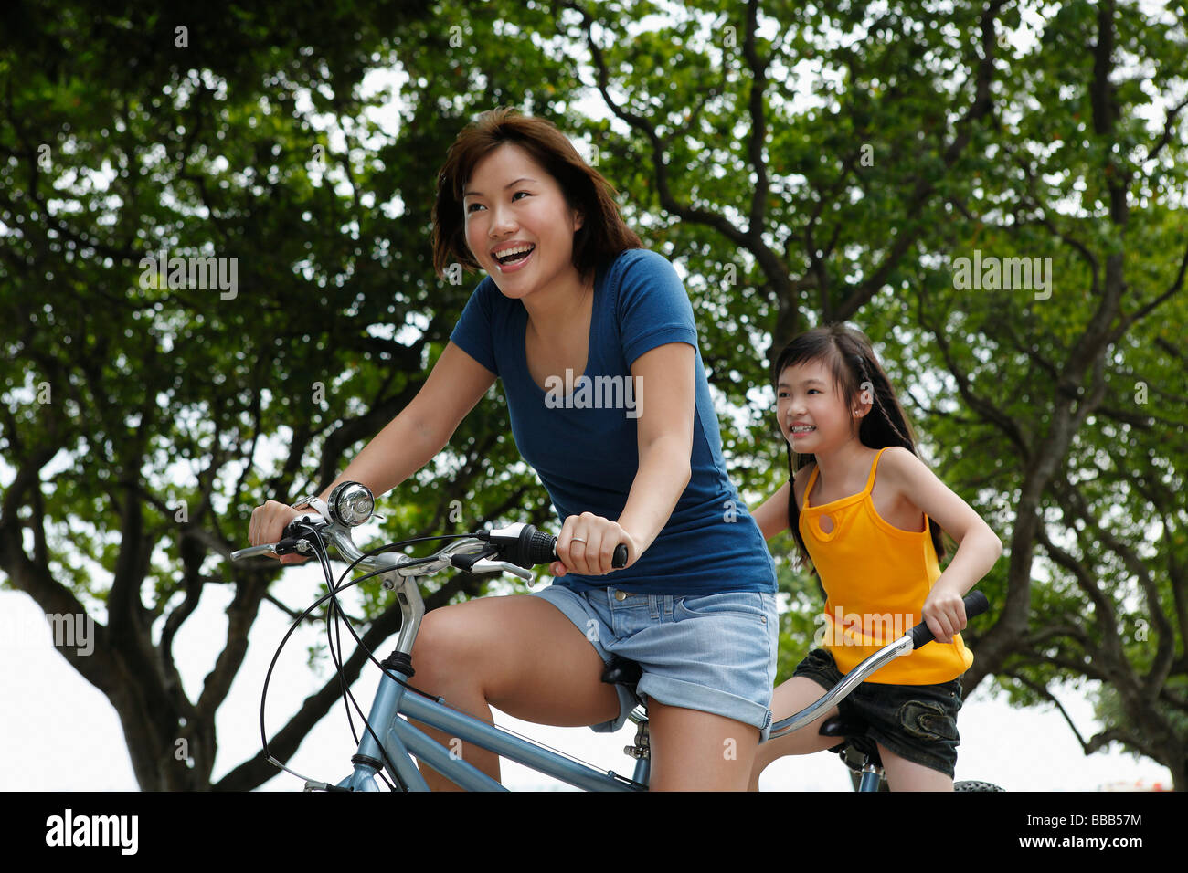 woman and young girl riding tandem bike Stock Photo
