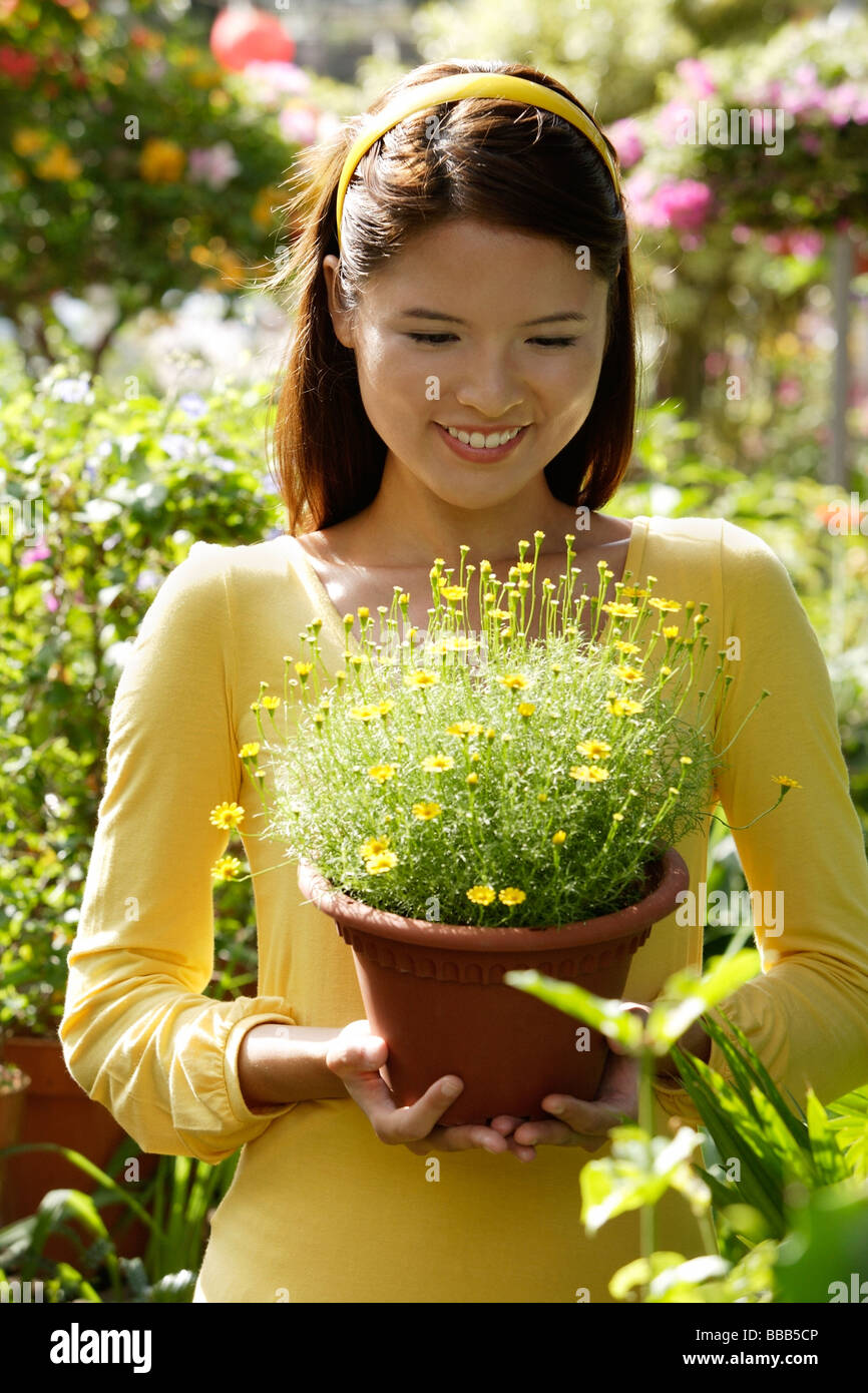 Young woman at nursery, holding potted plant Stock Photo - Alamy