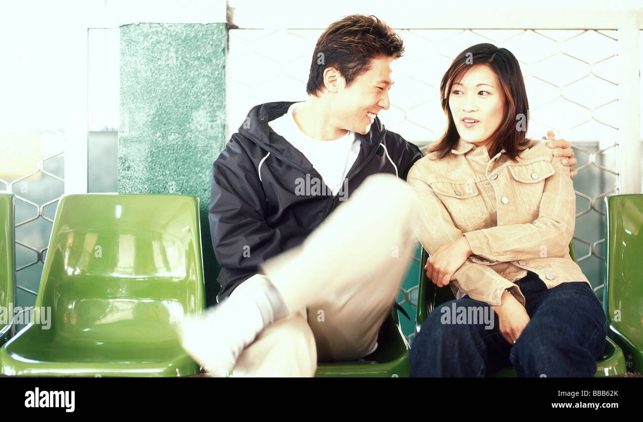 Young adult couple sitting on plastic chairs Stock Photo Alamy