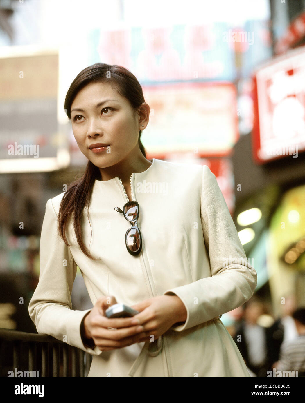 Woman holding cellular phone in busy street. Stock Photo