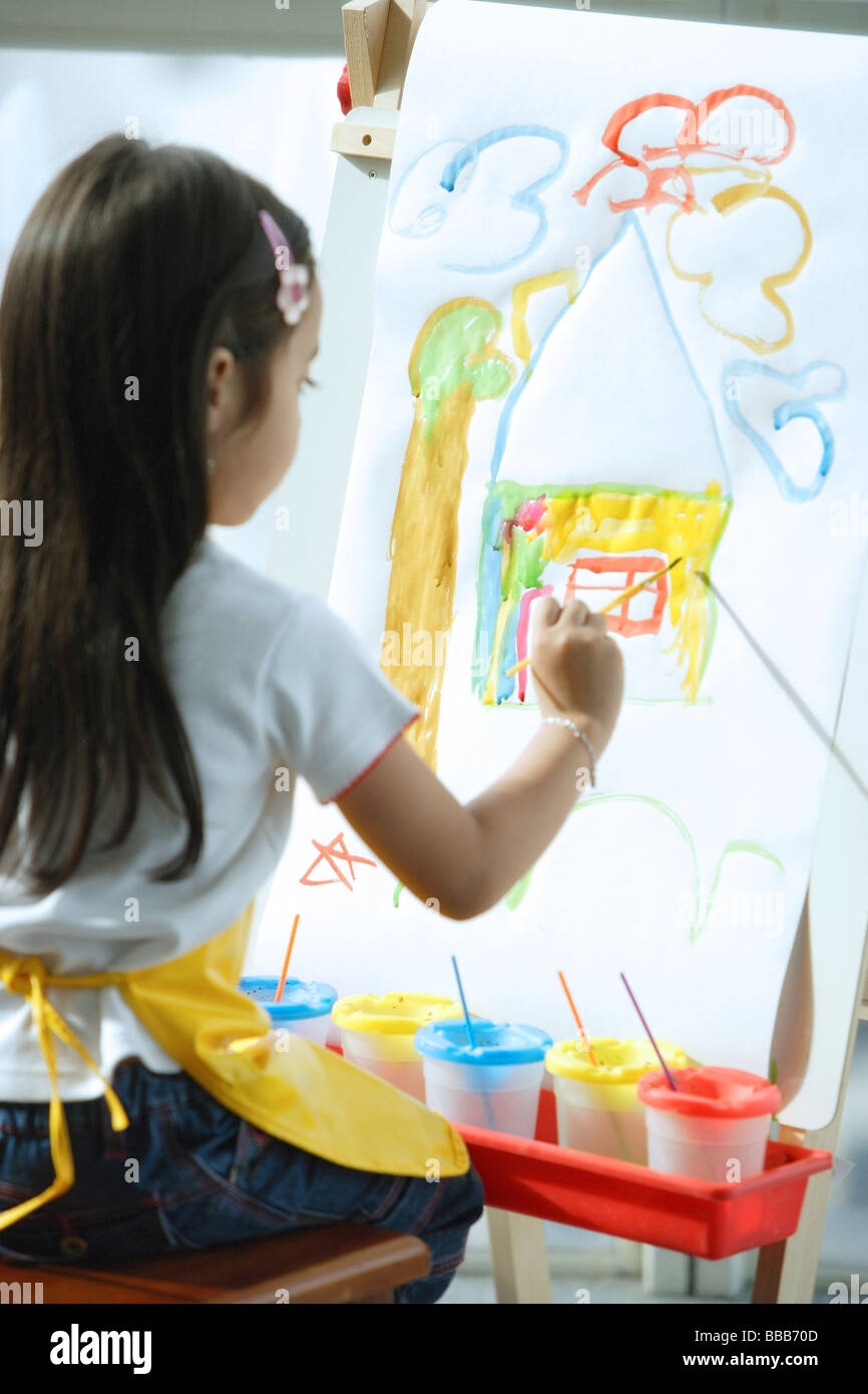 Young girl sitting in front of easel, painting Stock Photo - Alamy