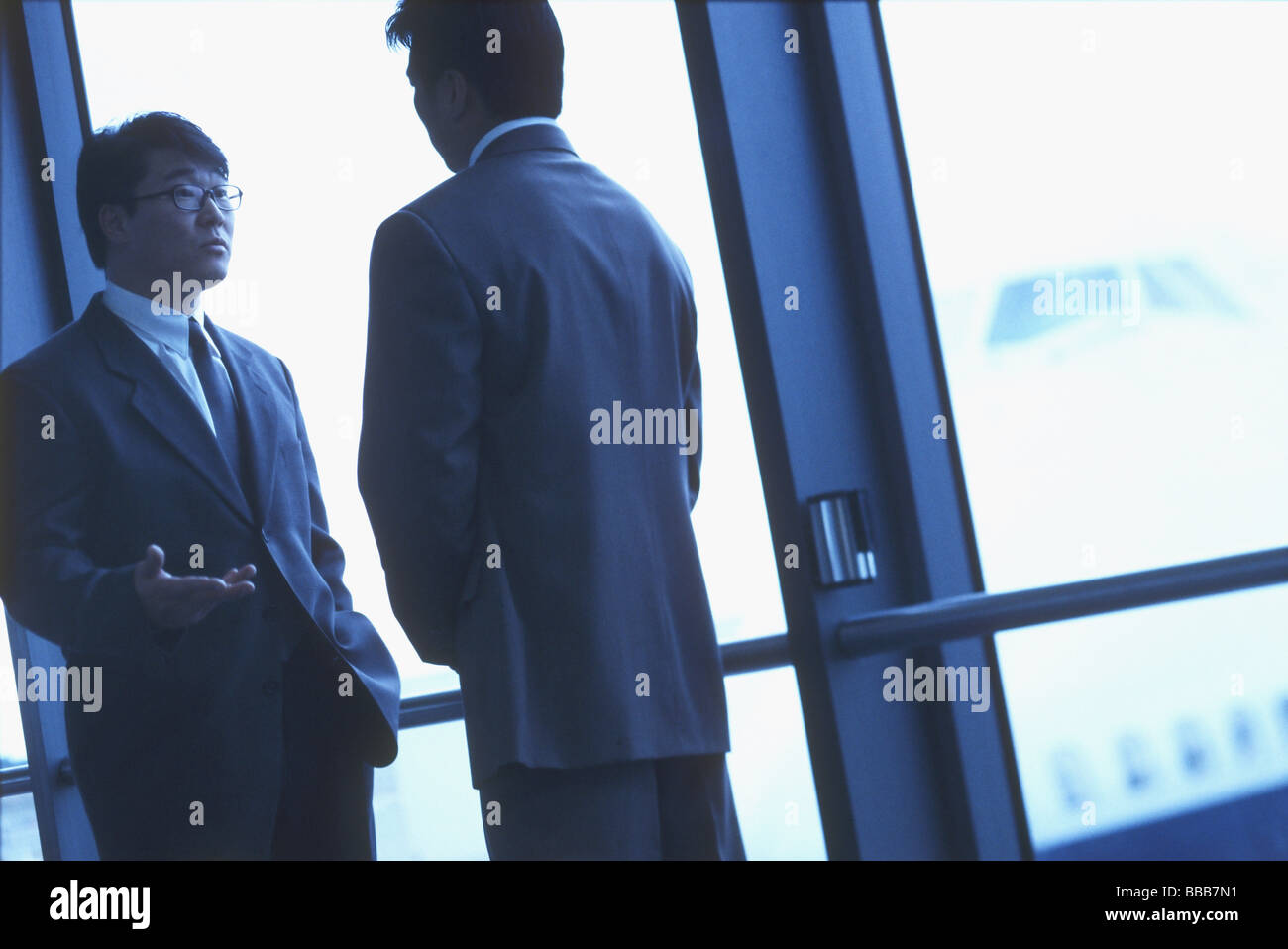 Two male executives talking in airport, silhouette Stock Photo