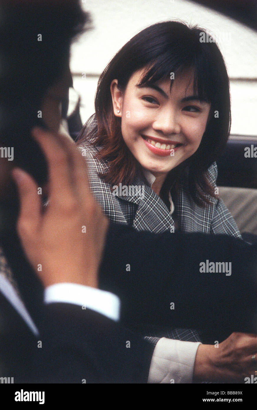 Female executive smiling at male executive talking on cellular phone in car Stock Photo
