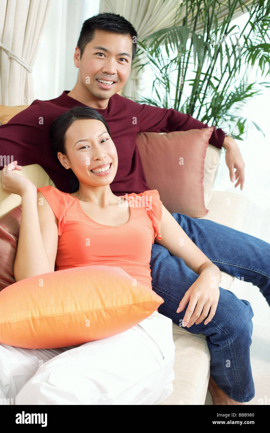 Couple in living room, sitting on sofa, smiling at camera, portrait Stock Photo