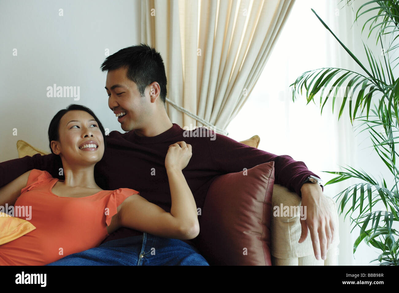 Couple sitting on sofa, woman leaning on man, looking up at him Stock Photo