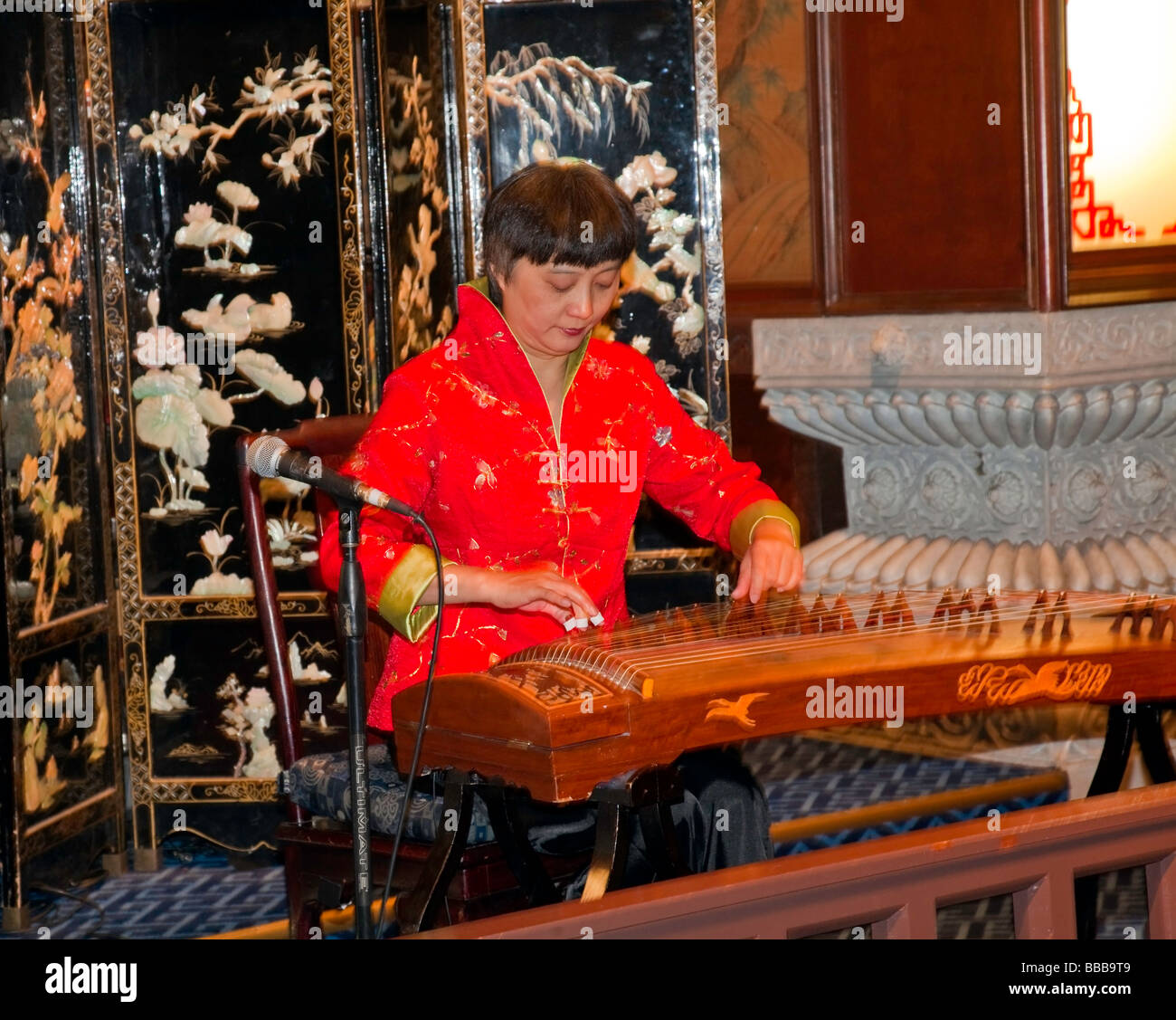 Chinese woman is making music on a tradition Chinese zither known as Gu