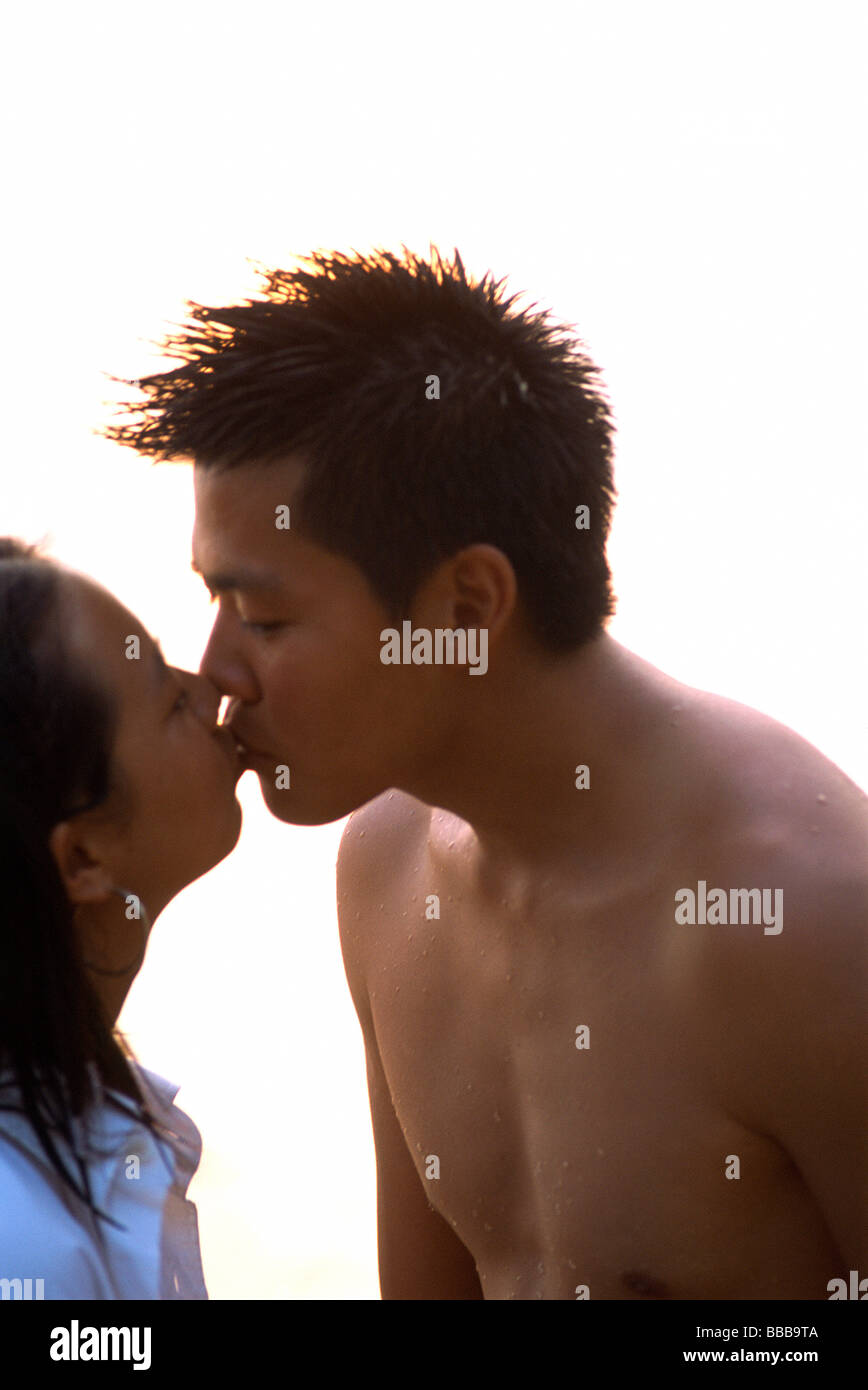 Young couple kissing, brightly lit background Stock Photo
