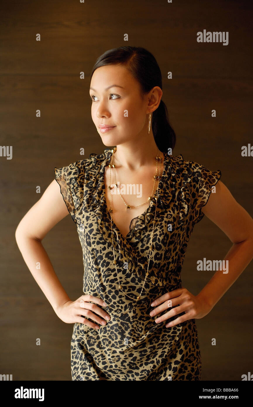 Woman in animal print dress, hands on hips, looking away Stock Photo