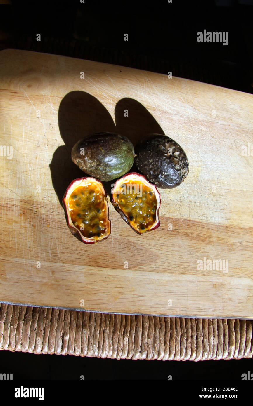 Image of three passion fruit, two whole and one split in half to show the fruit inside Stock Photo
