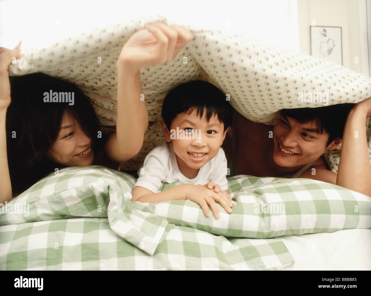 Parents and child in bed, playing Stock Photo Alamy