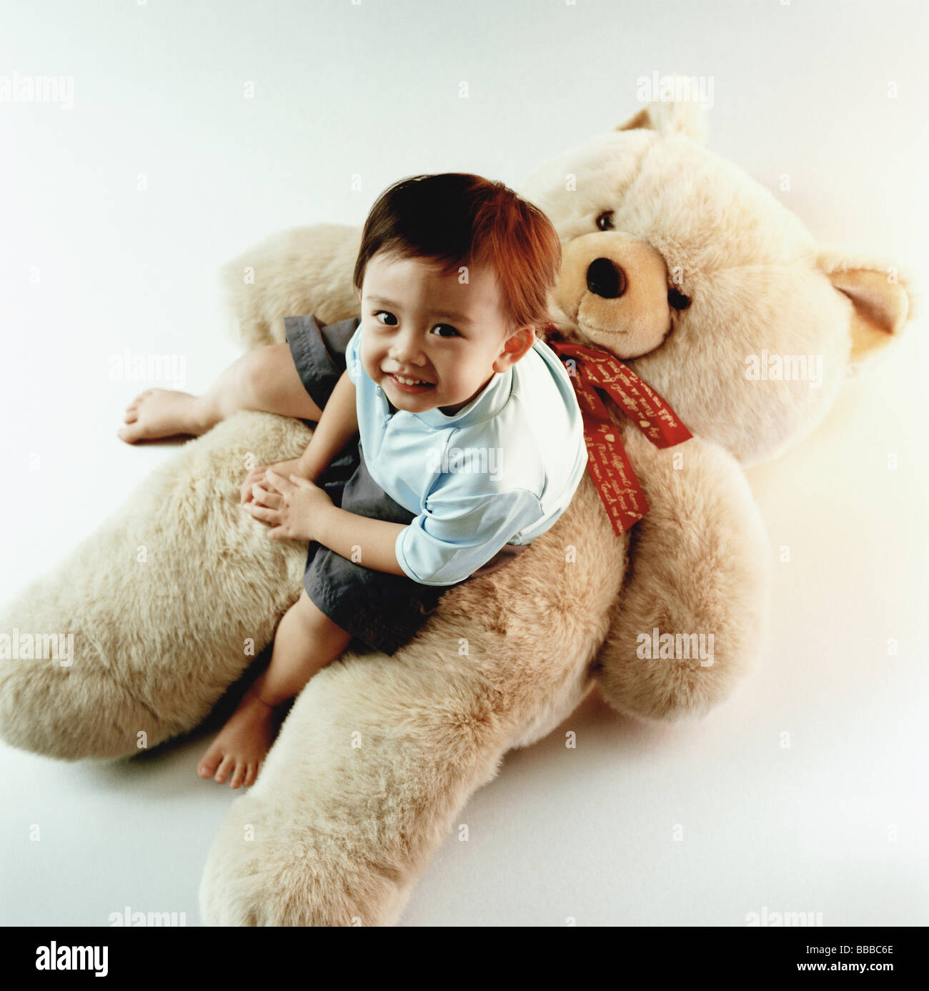 Young boy sitting on teddy bear Stock Photo - Alamy