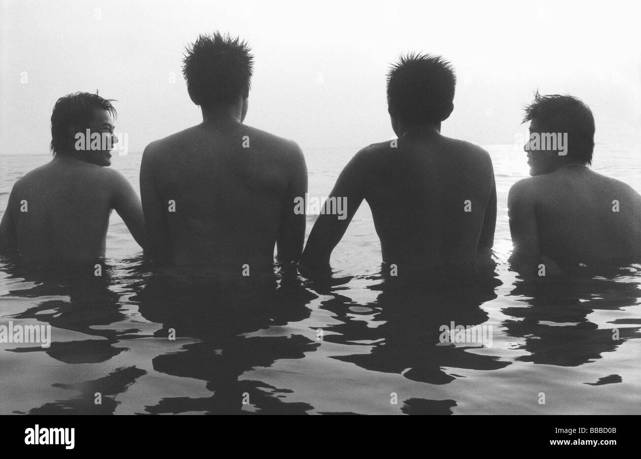 Teenagers wading in ocean, rear view, silhouette Stock Photo - Alamy