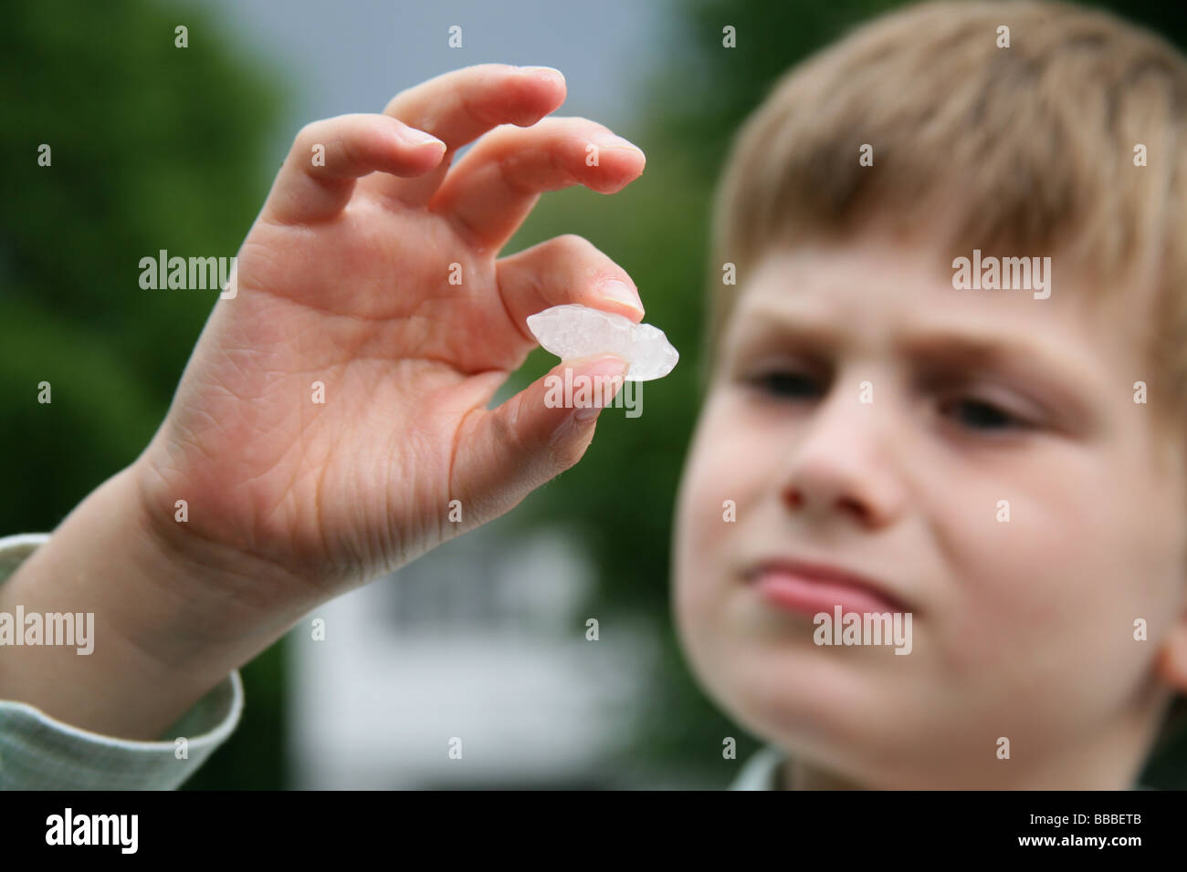 A young boy examines a hailstone that fell from the sky during a severe thunderstorm in Connecticut USA Stock Photo