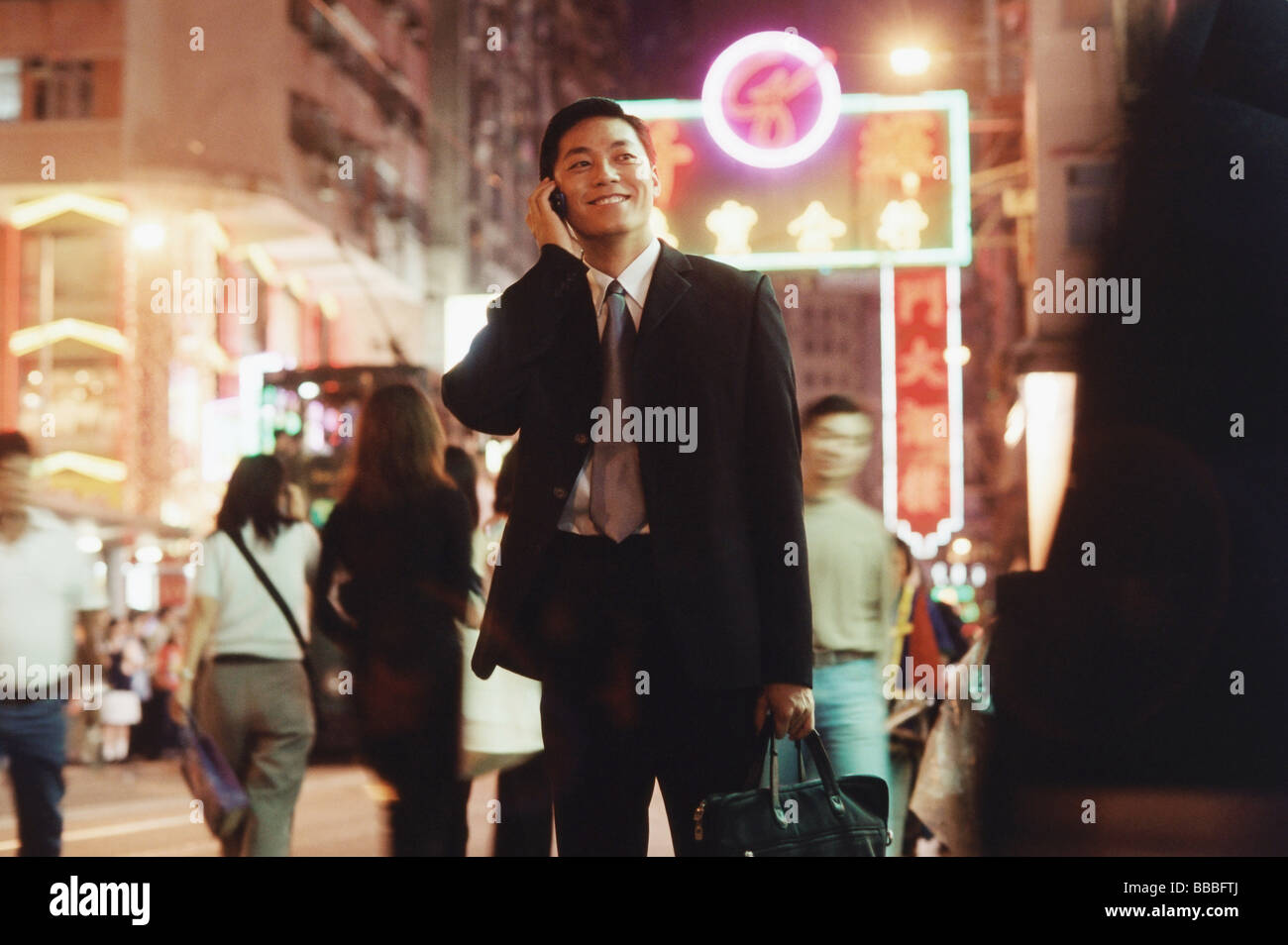 Hong Kong, male executive using cellular phone, carrying briefcase Stock Photo