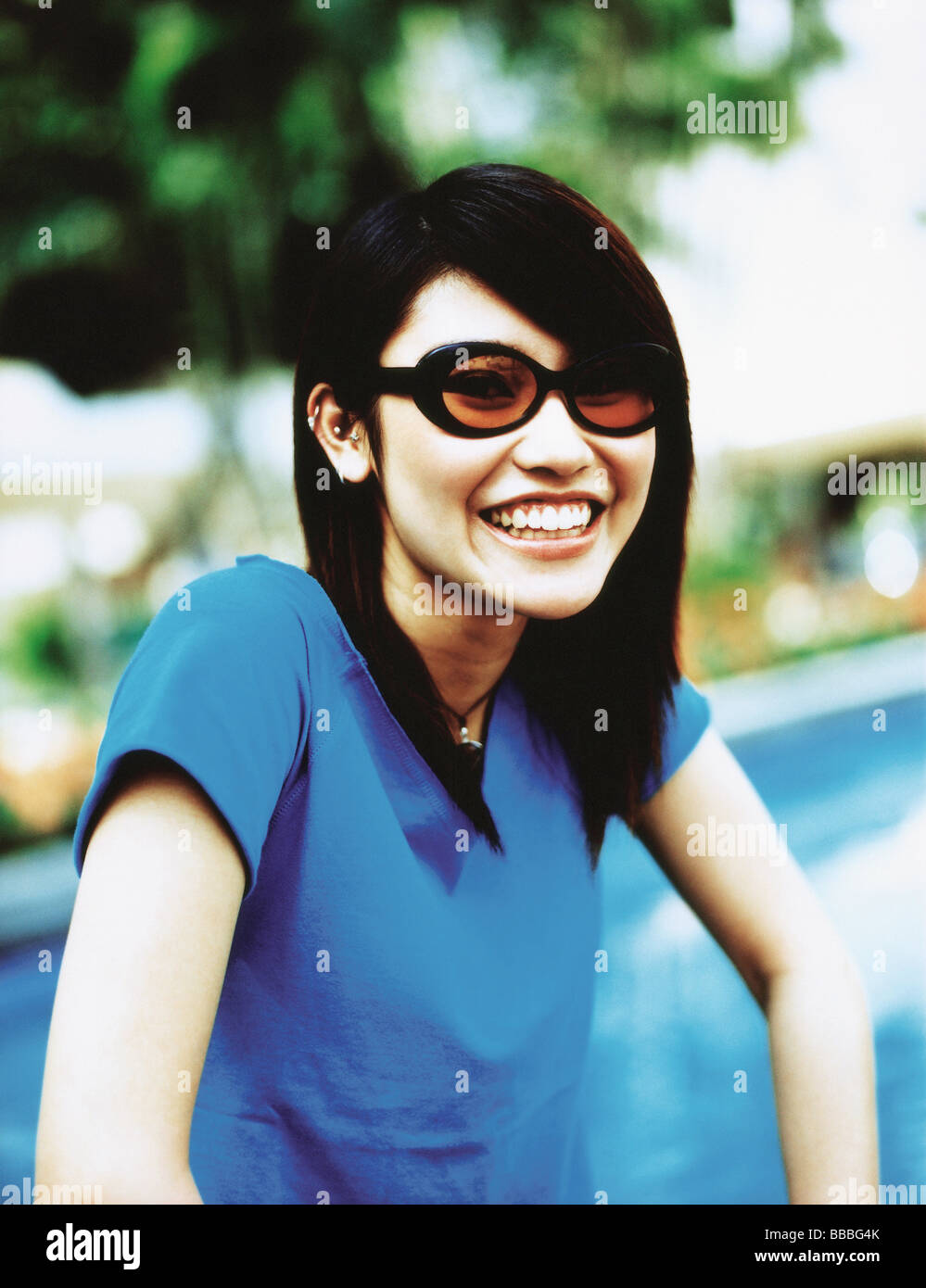 Young woman wearing sunglasses smiling, portrait Stock Photo - Alamy