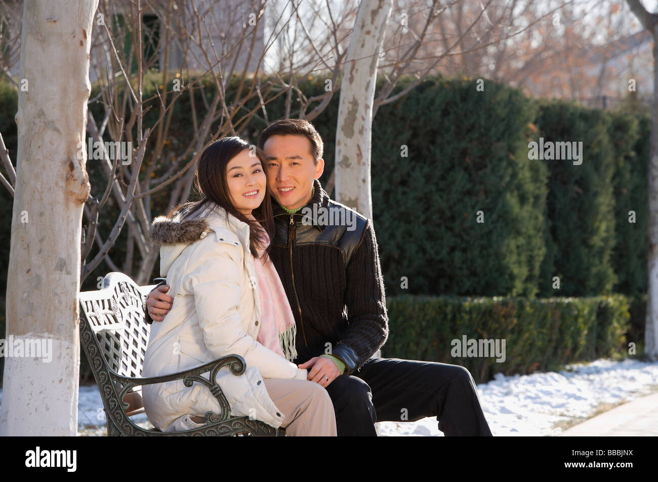Young couple sitting on park bench Stock Photo - Alamy