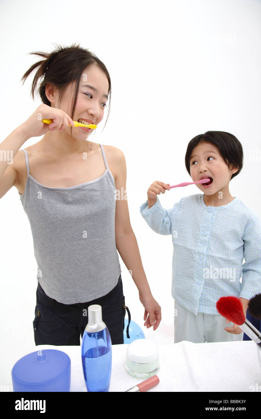 Mother and young daughter brushing teeth, looking at each other Stock Photo