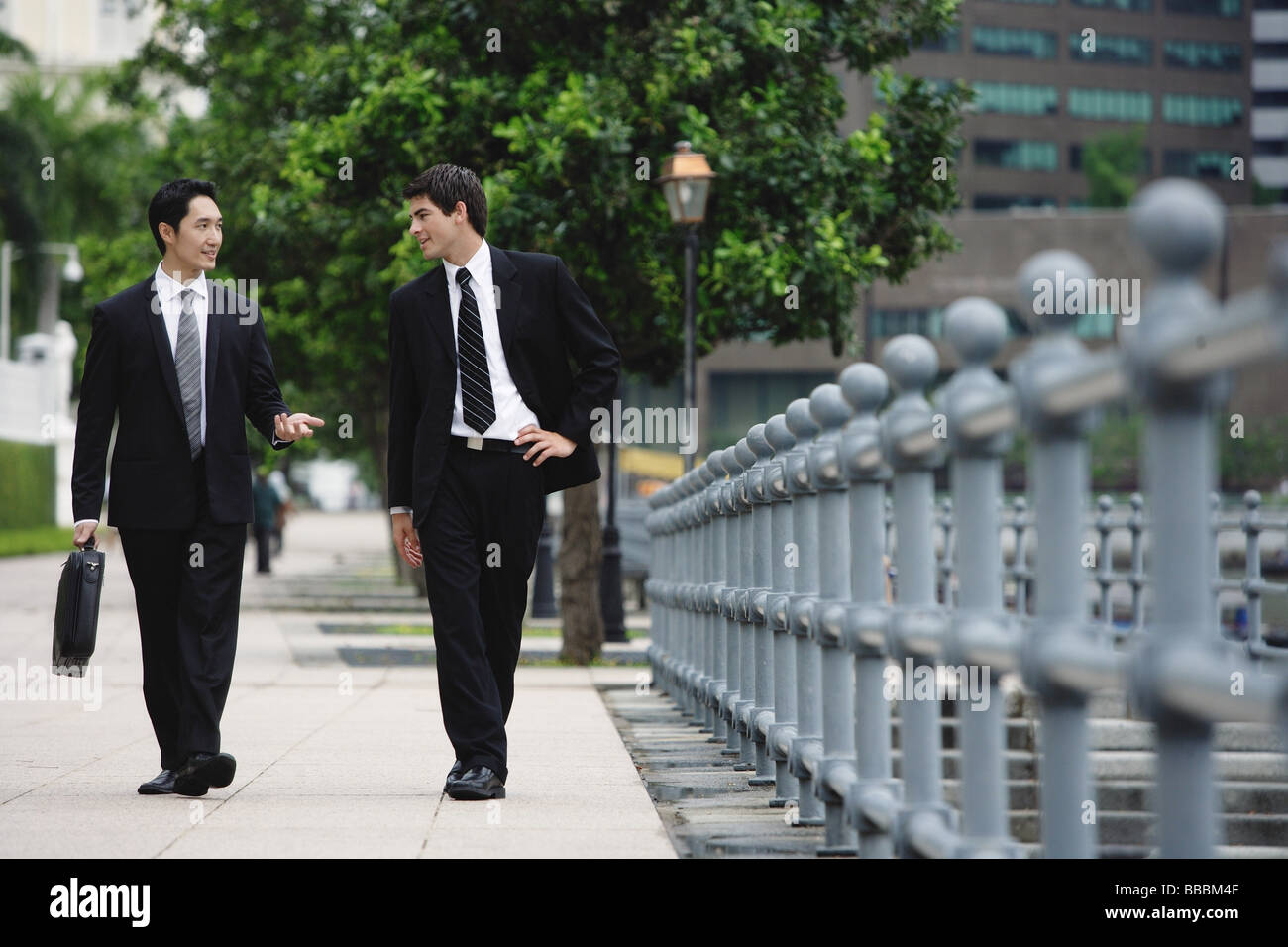 Two businessmen walking and talking Stock Photo - Alamy