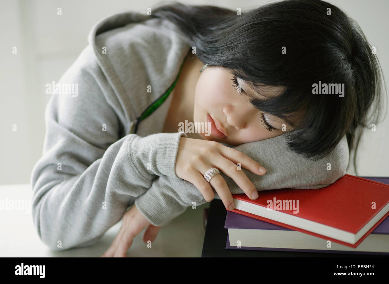 Young woman sleeping on stack of books Stock Photo - Alamy