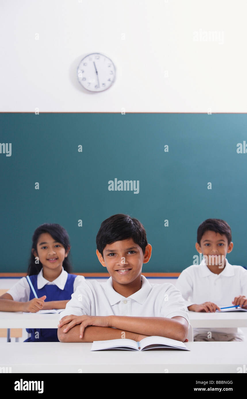 three students smile at camera, boy in center, arms folded Stock Photo ...