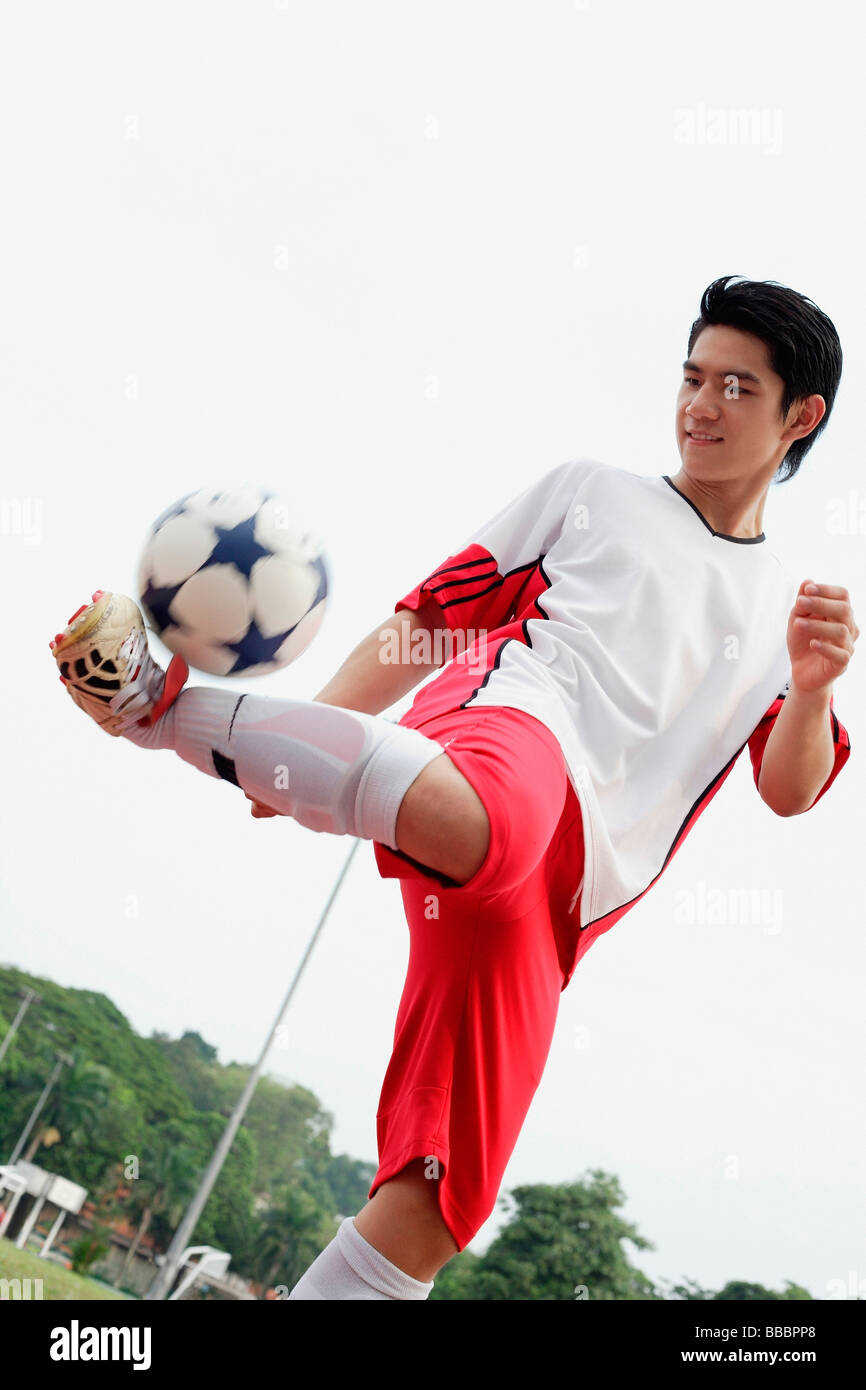 Young man kicking soccer ball Stock Photo - Alamy