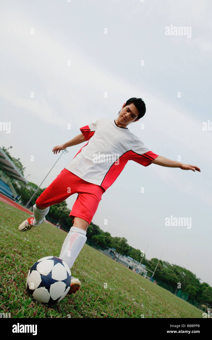 Young man kicking soccer ball Stock Photo - Alamy