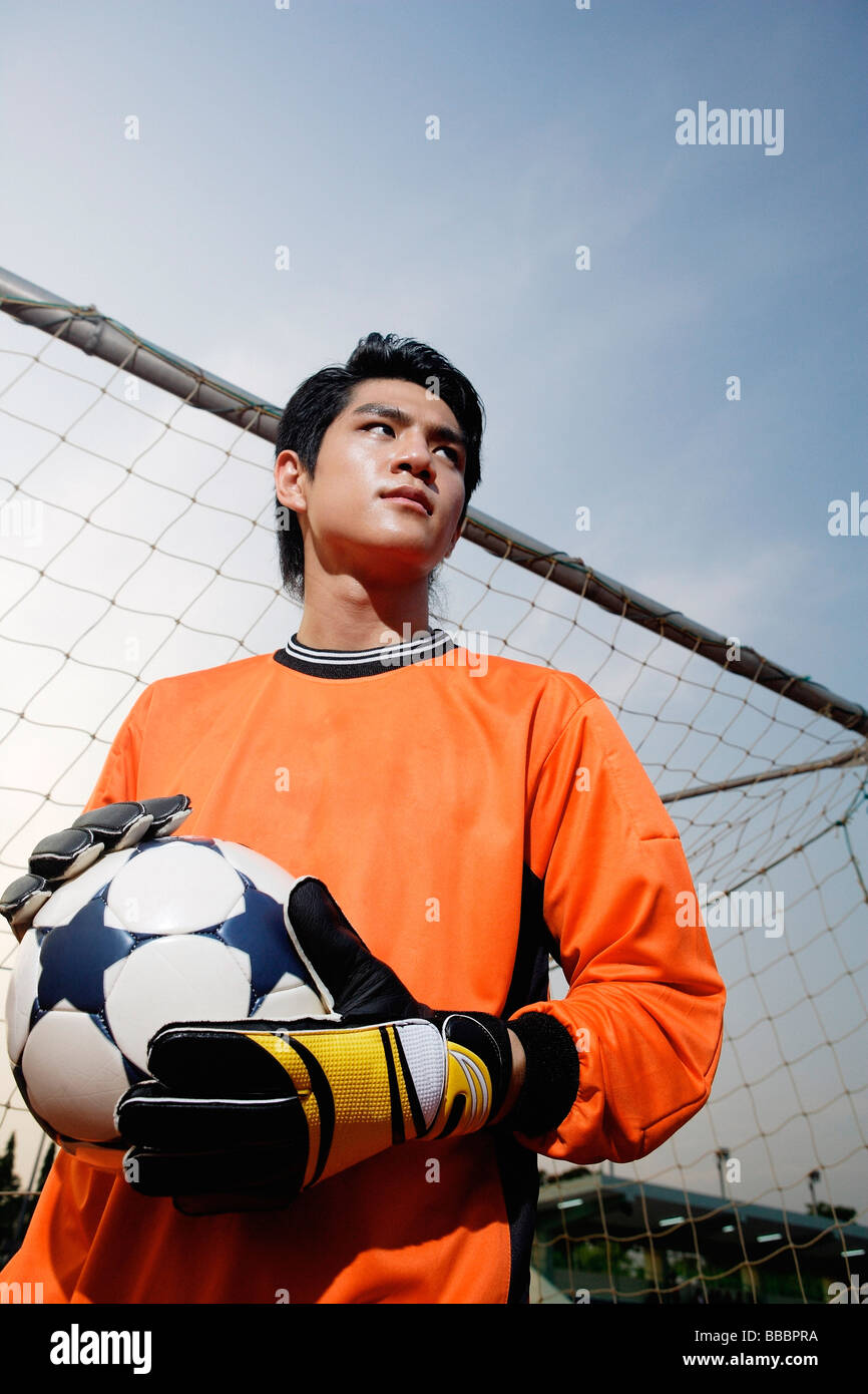 Soccer goalie standing next to goal post, holding soccer ball Stock