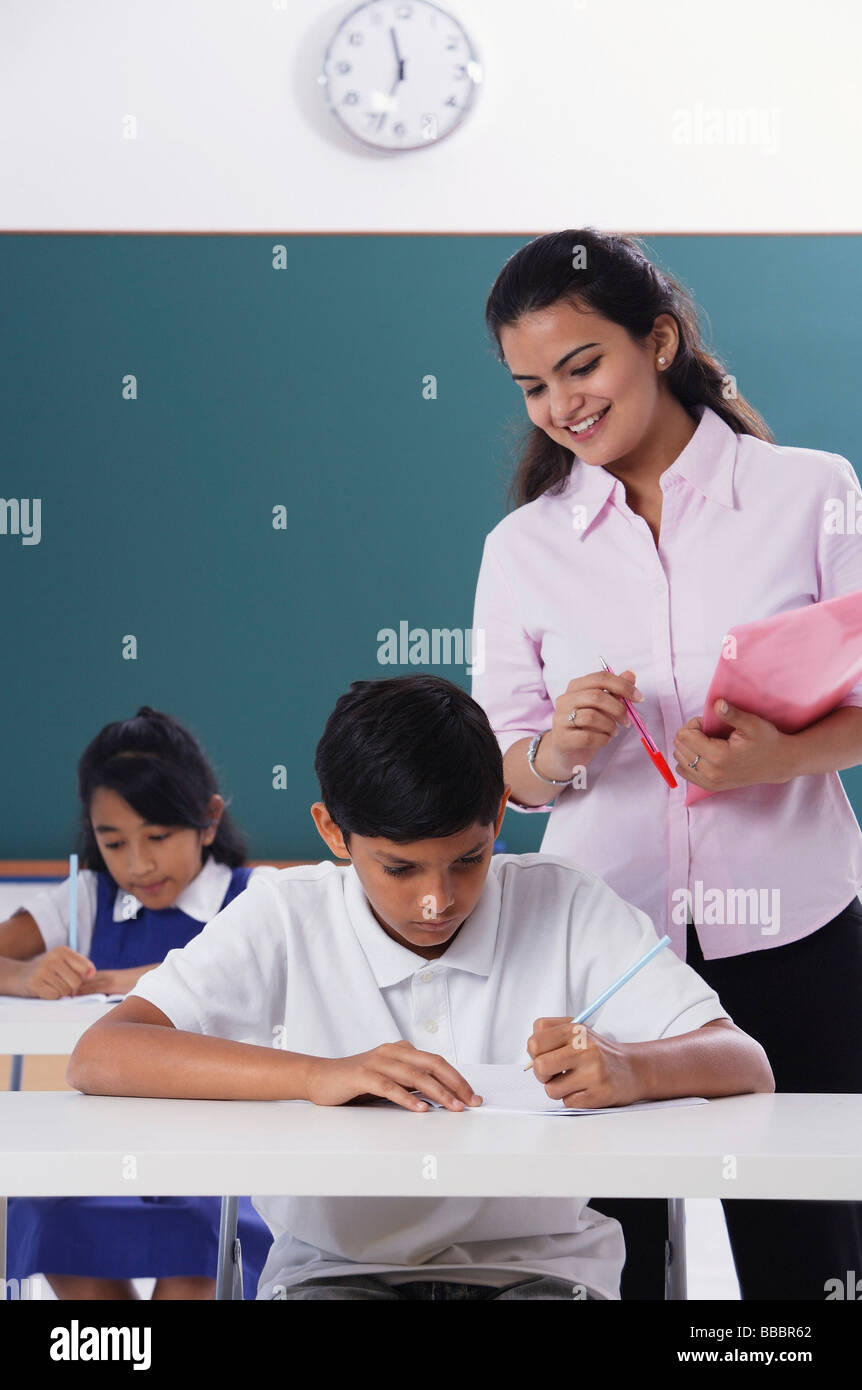 Two students desk teacher standing hires stock photography and images