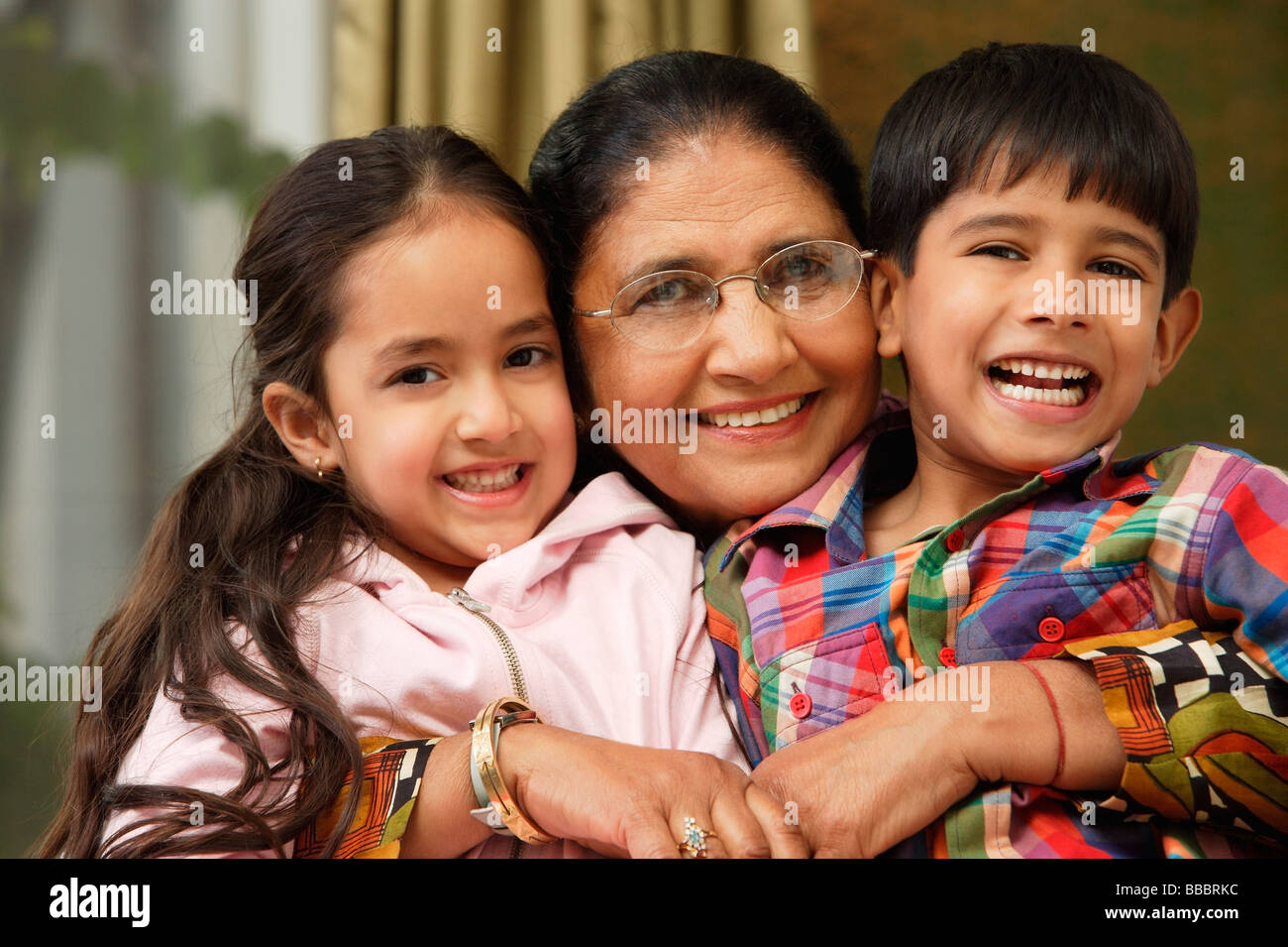 grandmother hugs grandkids, all smile at camera Stock Photo