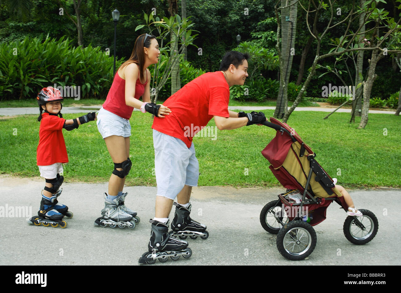 Family wearing roller blades, skating all in a row, father pushing