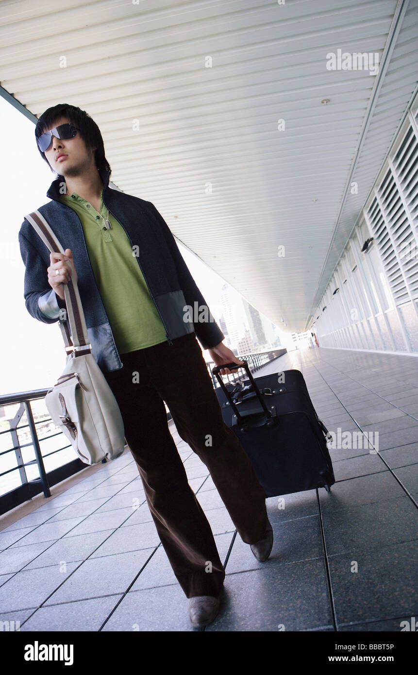 Young man pulling suitcase, walking Stock Photo