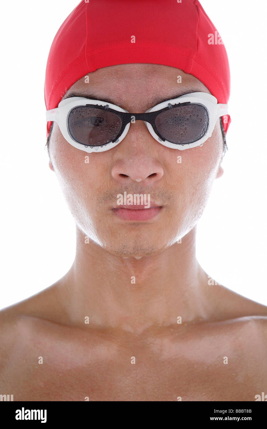 Young man wearing swimming goggles and swimming cap, face wet Stock Photo