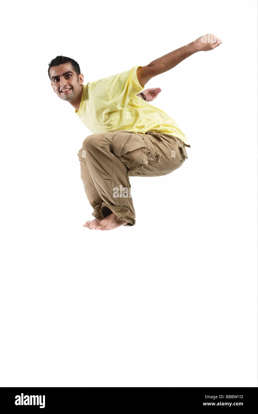 Young man jumping in mid-air, arms outstretched Stock Photo