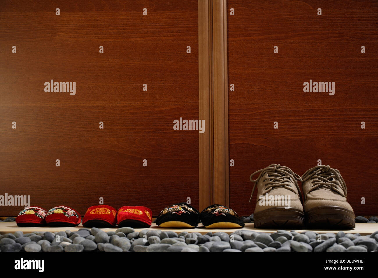 slippers and shoes placed in a row at door front Stock Photo