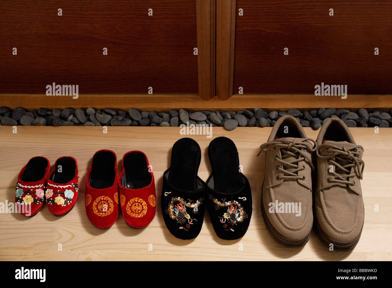 top view of slippers and shoes placed in a row at door front Stock Photo
