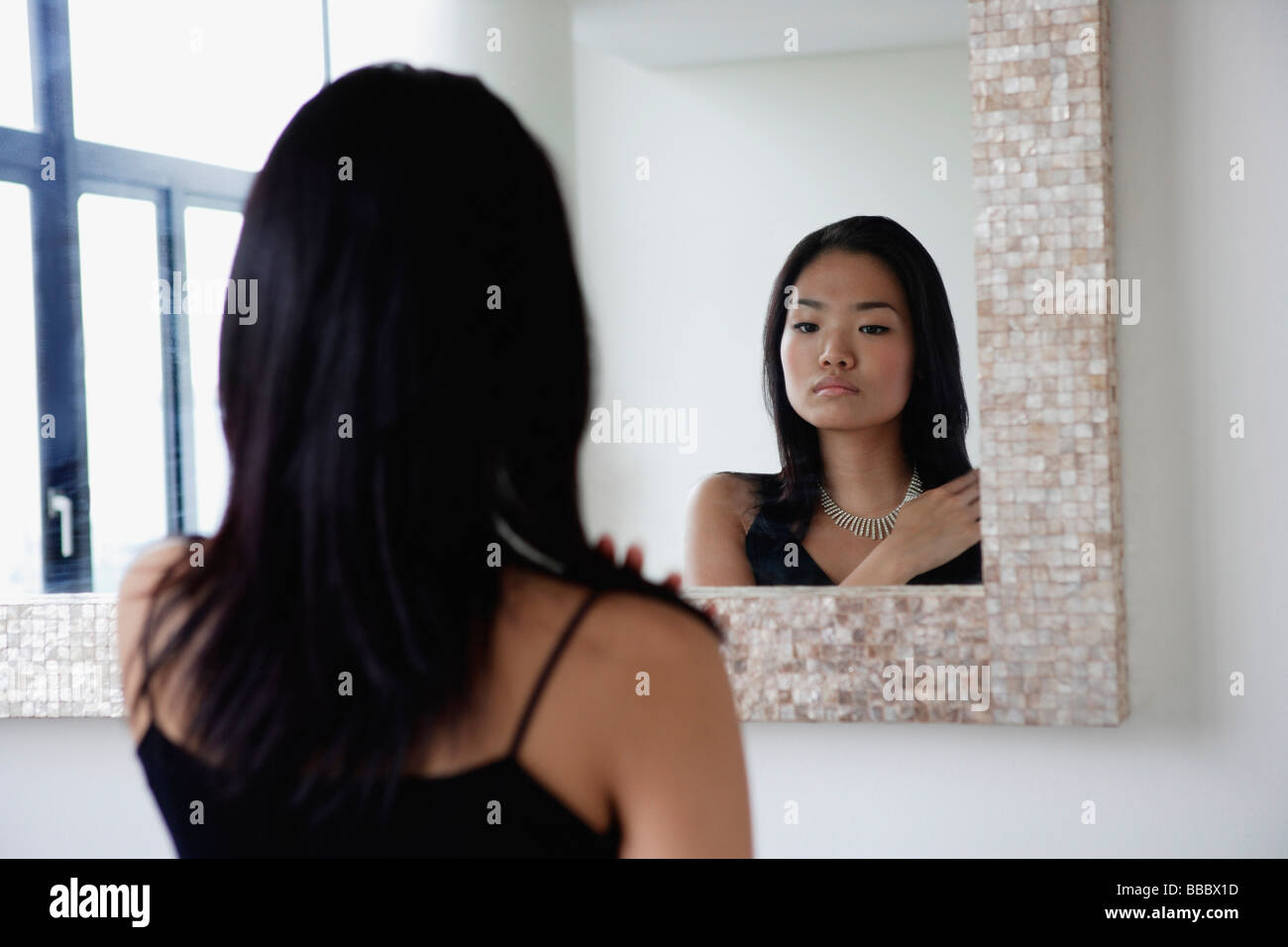 Young woman looking in mirror Stock Photo - Alamy